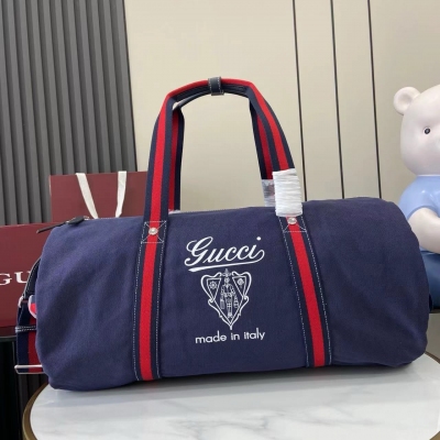 Gucci古馳 新品 以自由、活力與社群為主題，2025春夏系列煥新呈獻多款旅行單品和男士包袋，為出行探索更添妙趣。這款帆布旅行包頂部綴飾縫線細節，配以同色調皮革滾邊，正面飾以“Gucci Made in Italy”徽章印花。深藍色帆布