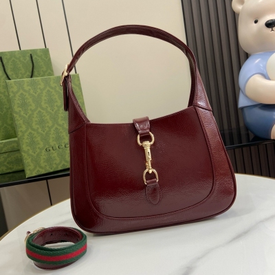 Gucci古馳 新品 Jackie系列小號肩背包。這款全新Gucci Jackie系列肩背包以上等優質皮革匠心打造，盡展品牌經典肩背包的精湛工藝、新月造型和時尚設計。淺金色調配件、皮革滾邊和飾有紅綠織帶的附贈包帶結合，為這款以酒紅色漆皮打造