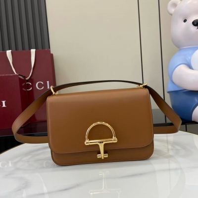 Gucci古馳 Siena系列煥新演繹品牌經典元素馬銜扣，打造魅力手袋單品。這款肩背包選用精細光面皮革匠心打造，挺括造型融蘊源自20世紀70年代的半馬銜扣搭扣設計細節。棕色光面皮革 金色調配件 棕色皮革襯裡 內部：3層接檔和1個拉鍊口袋 肩